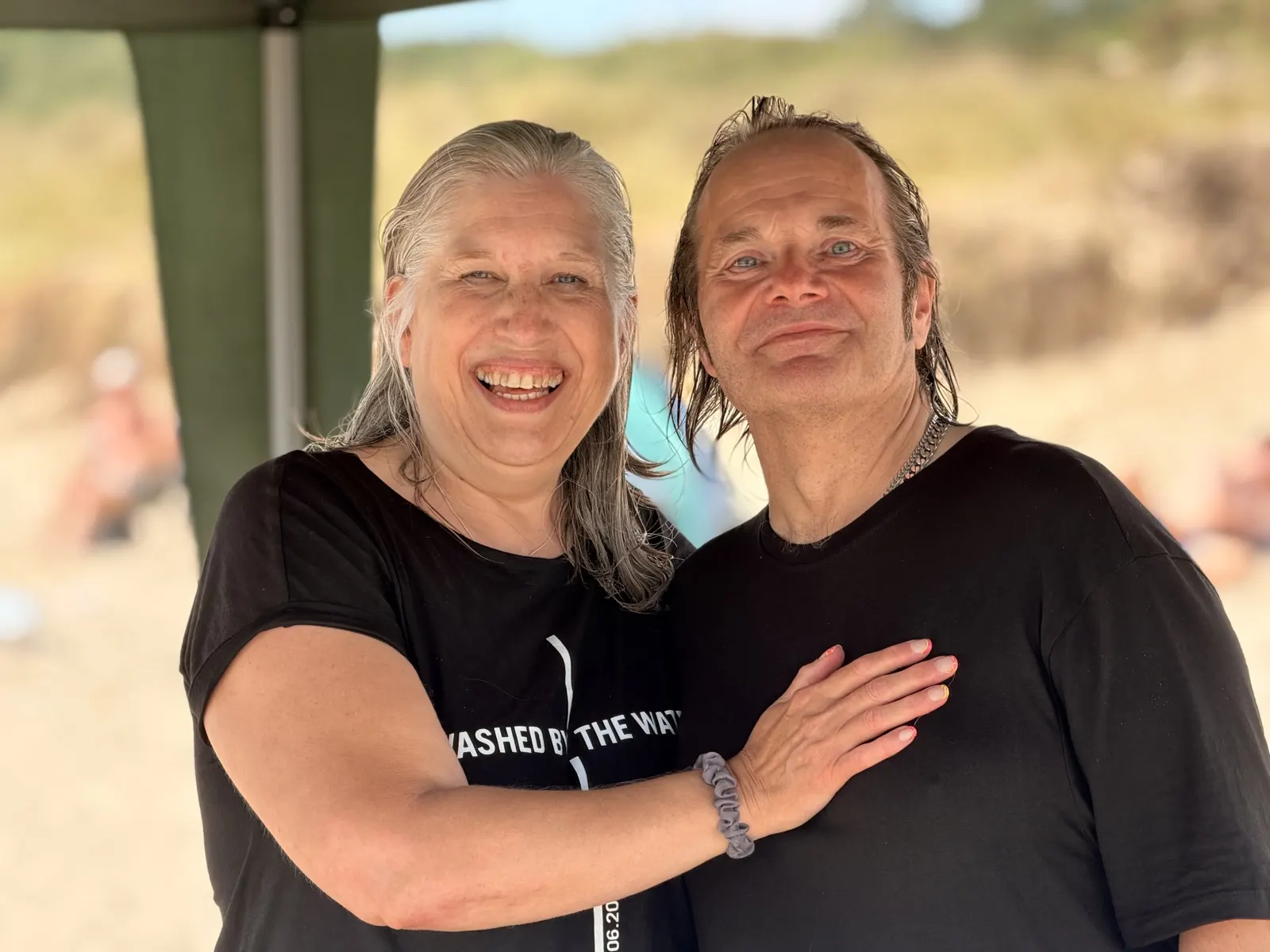 Two people hugging and smiling after being baptised, hair still wet